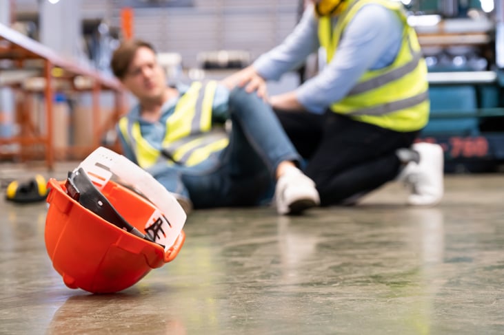 Hantover lock out tag out workplace accident, workers in hard hats inside of industrial factory setting receiving emergency assistance and help