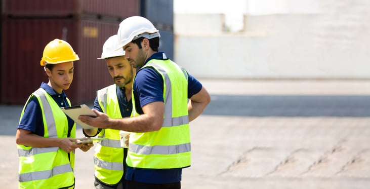 Group of professional engineering people wearing hardhats meeting and working with tablet