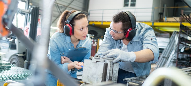 Two factory workers wearing protective earmuffs